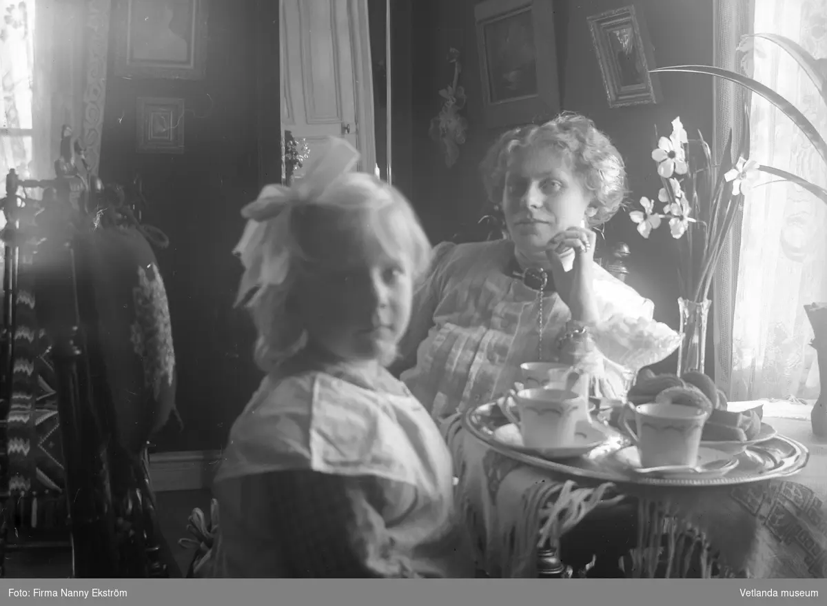 Kvinna och barn med bricka med fika. Kvinnan är troligtvis Mimmi Stenbäck, syster till fotografen Nanny Ekström.