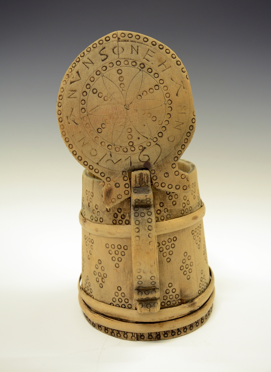 Drikkekanne i tre. Fra protokollen: Ølkrus av staver med svidde ornamenter. Paa laaket: Jon Anunsón E. H. A. Anno 1761.