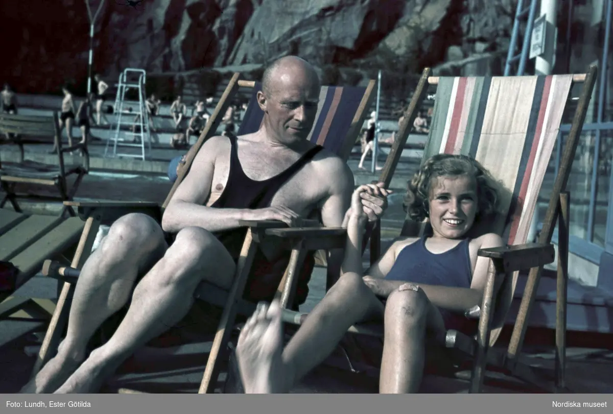 Bassängbad. Vanadisbadet, Stockholm. Fotografen Gunnar Lundh och hans dotter Jytte sitter i varsin solstol iklädda baddräkter.