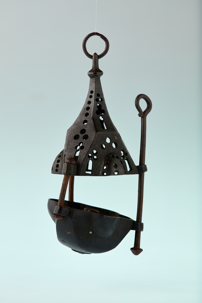 Bronse. 6 sidet. 3 av sidene med kuleformet utvidelse. Skål med pipe i centrum. Firpassformen viser hen på slutten av middelalderen. Den skjematiske og grove utførelse tyder på hjemlig produksjon. Ligger nær å gjette på Tunsberg. Etter reformasjonen er en lysepipe satt inn. Mulig denne lysestake har hengt etter en snor og likeledes den lange glidestangen