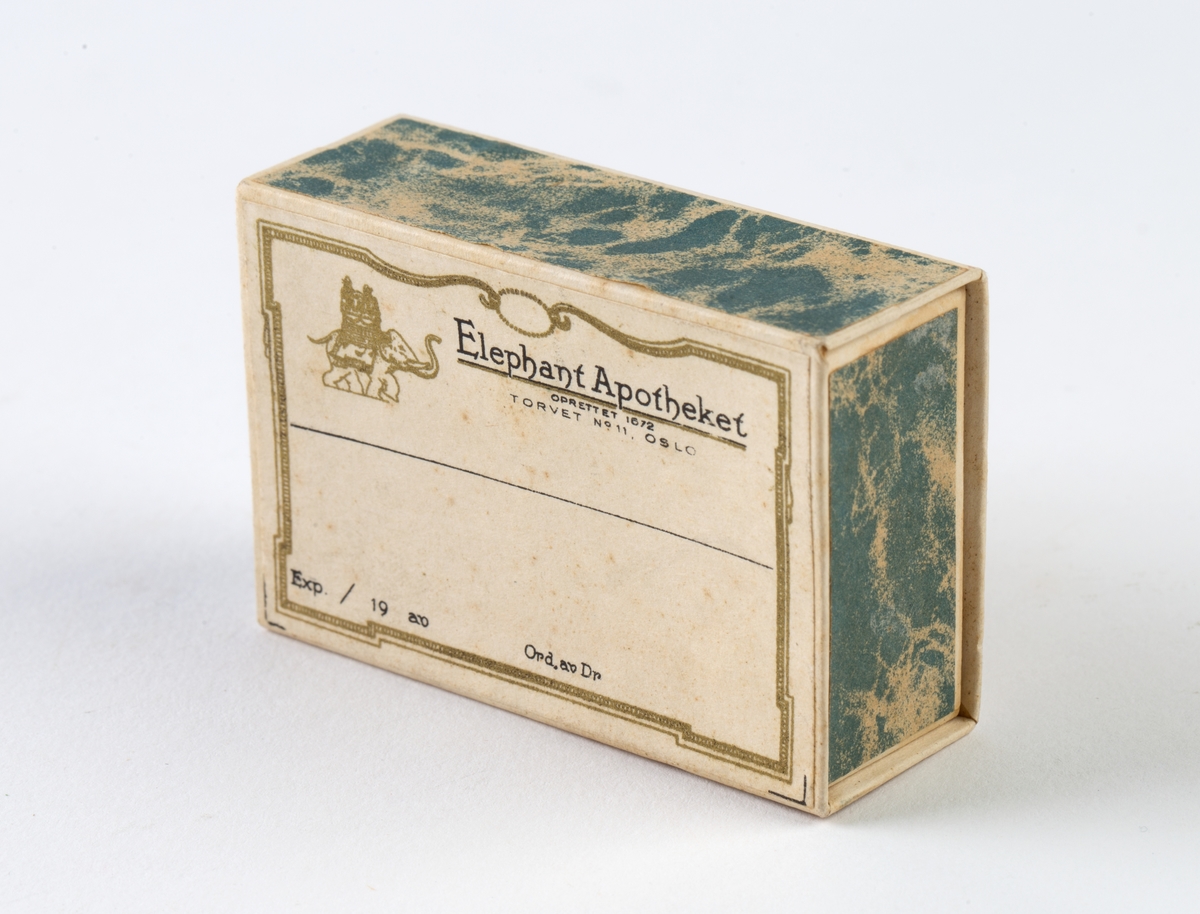 Firkantet pappeske. Uten innhold.
Logo til Elephantapotheket. Eske med skyvelokk.