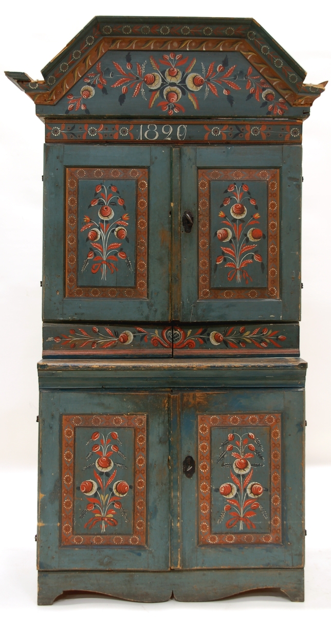 Allmogeskåp, målat i blått, vitt, rött och gult. Årtal målat 1820. Två luckor i underskåpet och två på överdelen. Två lådor på överdelen, skedhäck samt en hylla i överskåpet, en hylla i underskåpet.