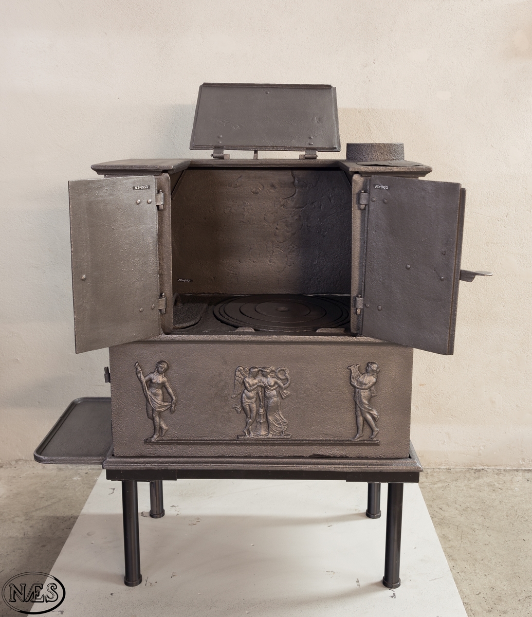 Kokeovn i to etasjer med eget fyrkammer og kokerom. Kokerommet kan åpnes med to dører på langsiden og med en luke i topplaten. Ovnsdøren til fyrkammeret er på kortsiden 1 etg. På langsidene i 1. etg er det tre muser og en engel med lette draperier på en enkel profillist. På kortsidene 2. etg er det draperikledd dansende muse på enkel profillist med en rosett i hvert øvre hjørne. Langsidene i 2.etg er dekorert med en rosett i hvert øvre hjørne.