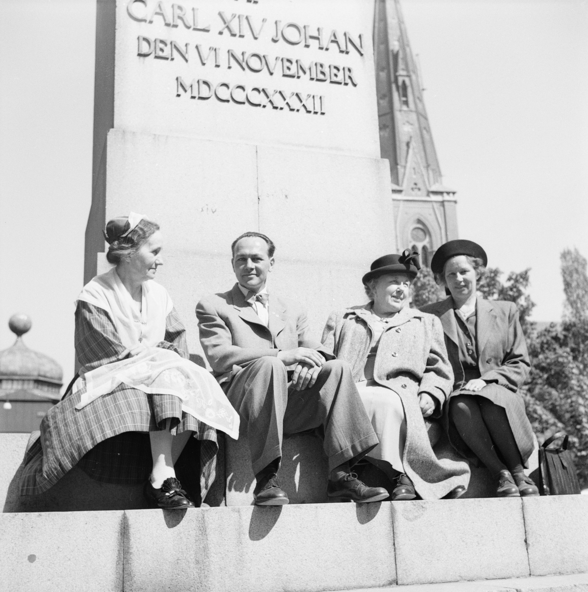 Man och kvinnor vid obelisken i Odinslund, Uppsala