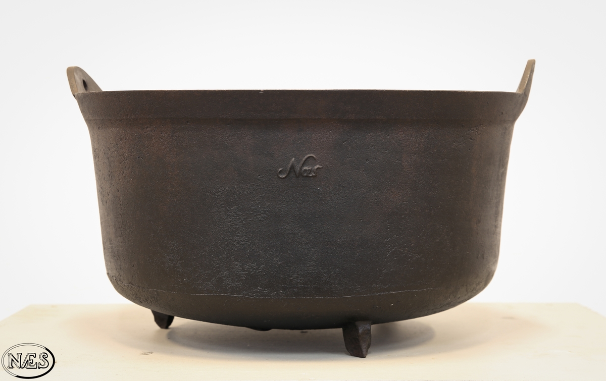 Rund jerngryte med tre bein og to ører på øvre kant for feste av hank.