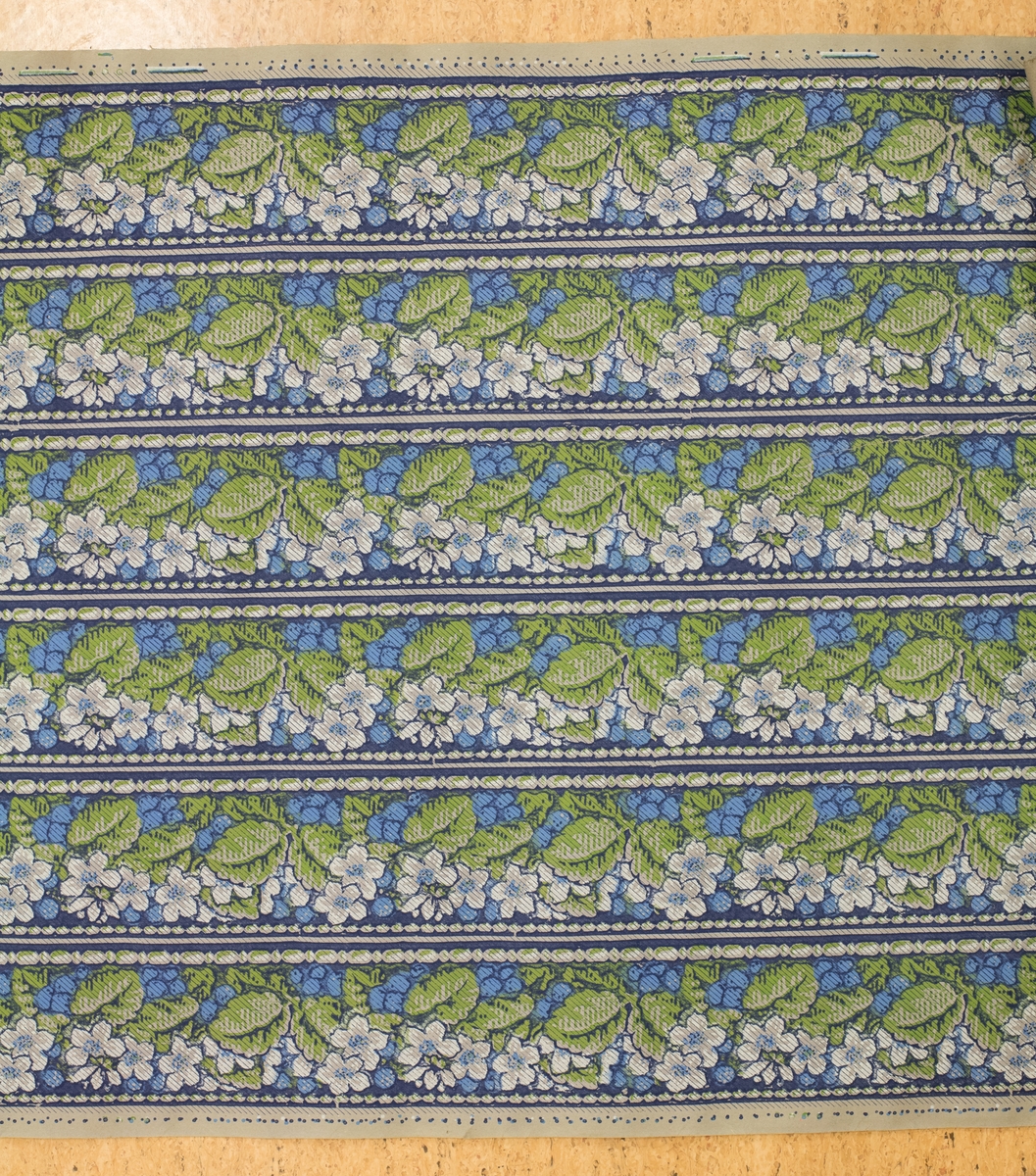 Tapetrulle med sex rader med tapetbård. Dekor med vita blommor bland gröna blad och blåa bär.