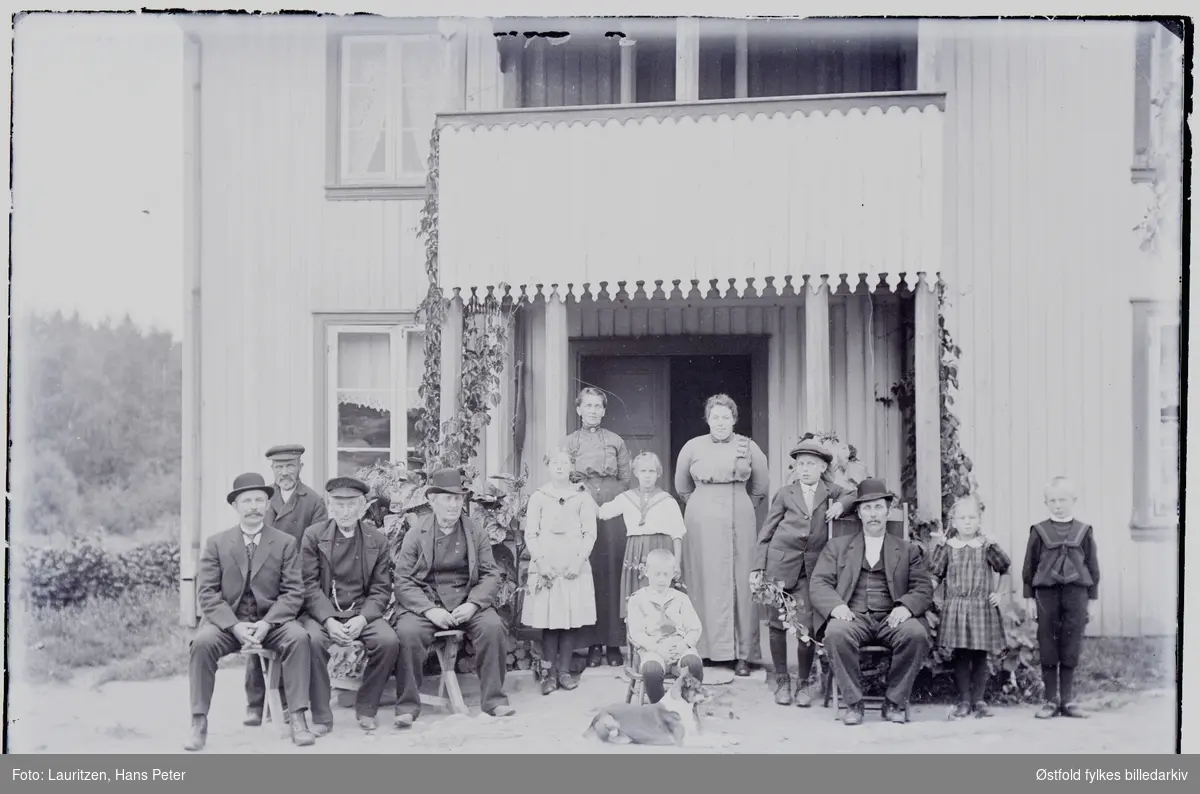 Familie foran hovedinngangen på gården Sletta i Såner, 1910-15.
Stående i døråpningen: Martha Lovise Hermansdatter og sittende til høyre hennes mann: Karl Hjalmar Larsen Sletta.
