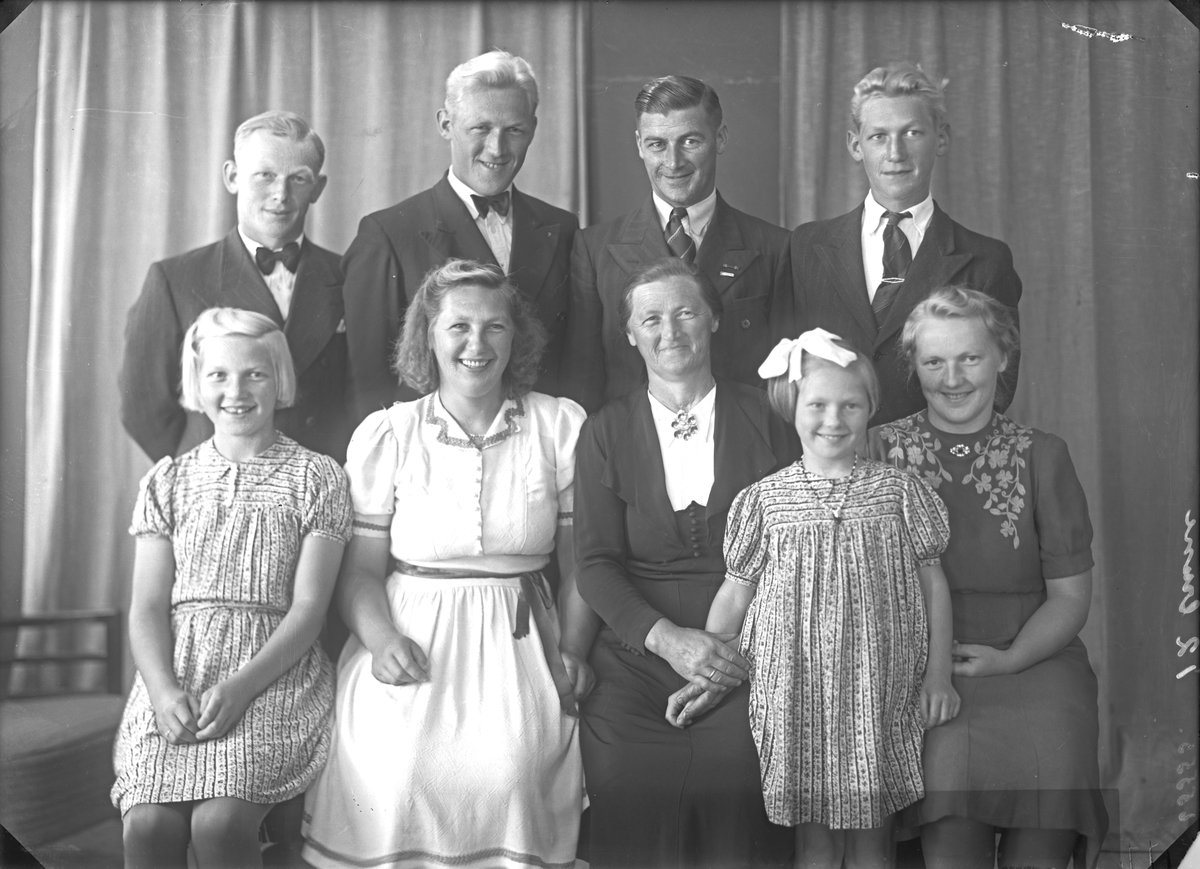 Gruppebilde. Familiegruppe på ni. Mann, kvinne, tre unge menn, to unge kvinner og to piker. Bestilt av Johan Rossehaug. Sveio.