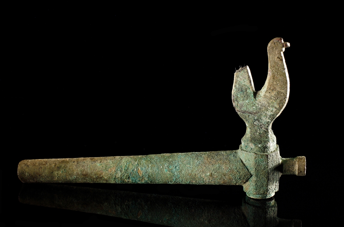 Krantapp av brons inklusive ölhane i kvarsittande i läge. Ölhanen formad som en tupp (stjärten dock ngt ofullständig) Vredhållaren är mångkantig och försedd med ett utsprång.