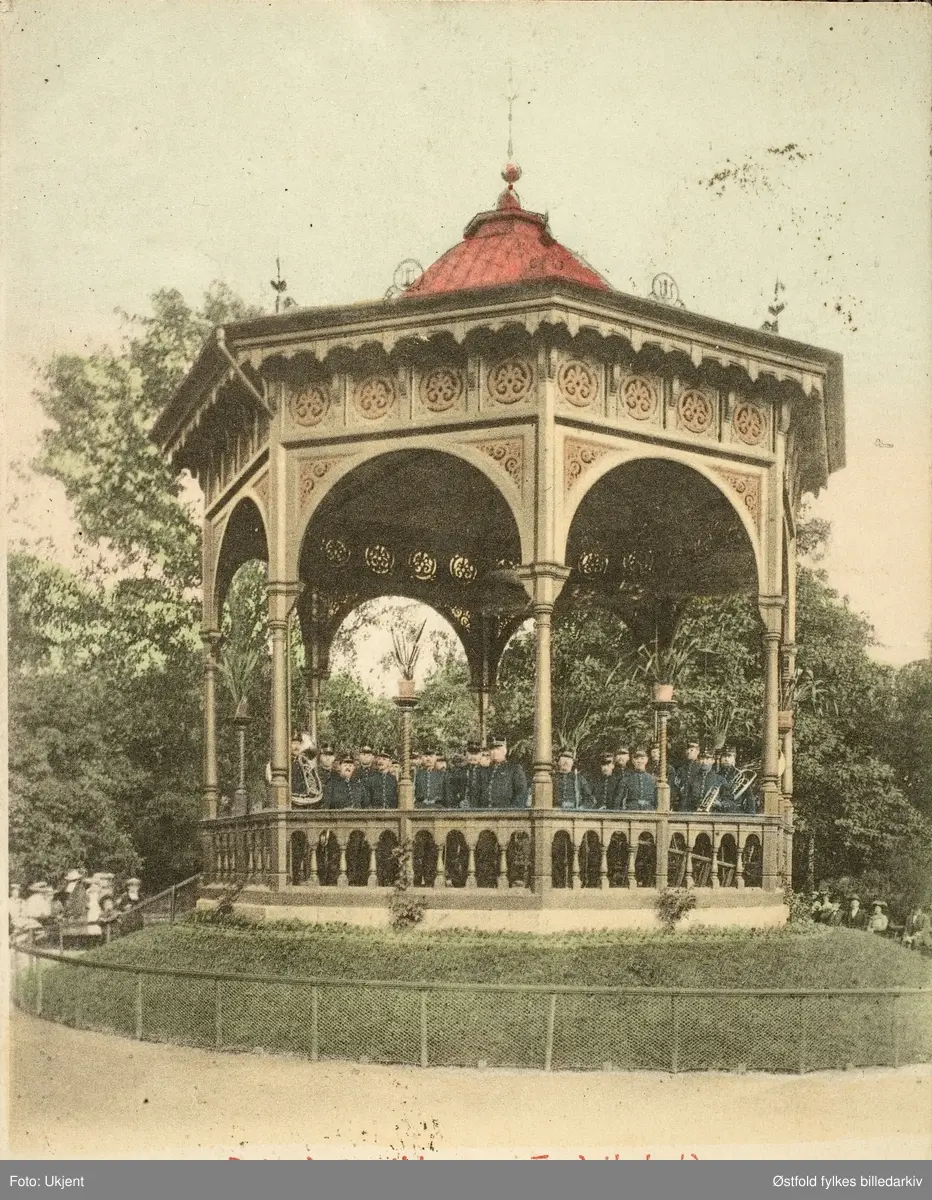 Postkort, kolorert lystrykk av paviljong i Halden der Brigademusikken spiller, 1903.