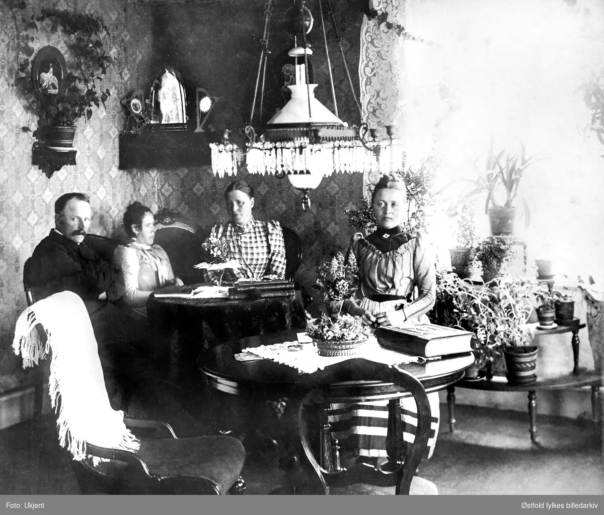 Stueinteriør fra hjem på Larkollen i Rygge 1892. Hjemmet til Carl E. Iversøn.
Fra venstre: 
Carl Emerntius Johannesen Iversøn (1838-1930) (dampskipsfører), kona Hedvig Jacoba Iversøn (1852-1935), Dikka Abel, Karen Bredal. 
Ifølge folketelling 1910 for Rygge var Carl og Hedvig bosatt på Fagerheim, Larkollen i Rygge.