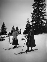 To kvinner med skjørt på skitur.