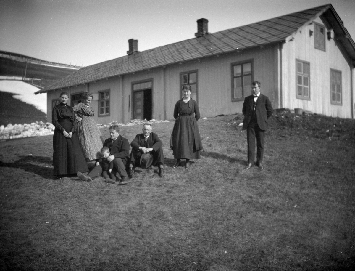 3 kvinner, 3 menn og et barn i bakken utenfor Breidablikk skule, Brekkom i Ringebu. Lærer Ole Sjetne nr. 3 fra venstre.