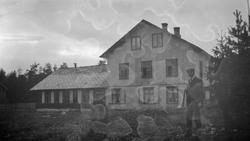 En mann står forran Bølund skole, Vålebru. Uklart bilde.