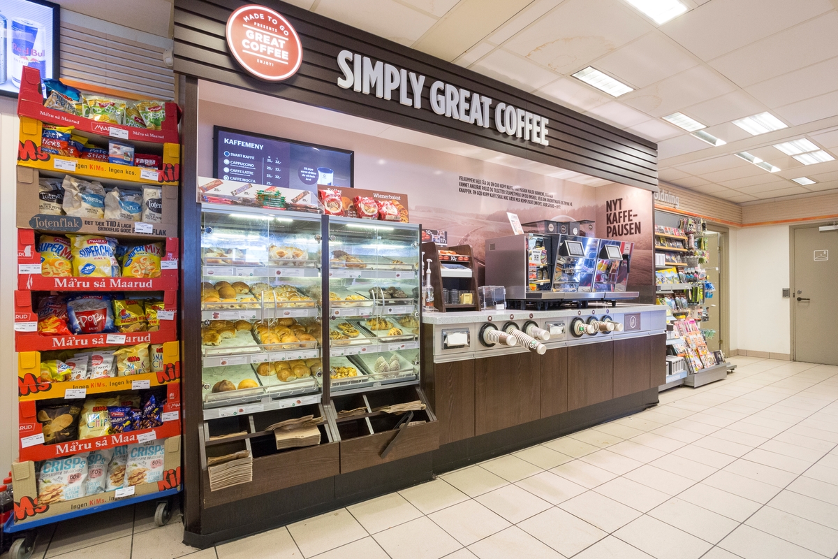 Statoil Nadderud. Butikk interiør med veggseksjon med kaffeautomat, engangsbegre, tilbehør til kaffe og ferske kaker og boller.