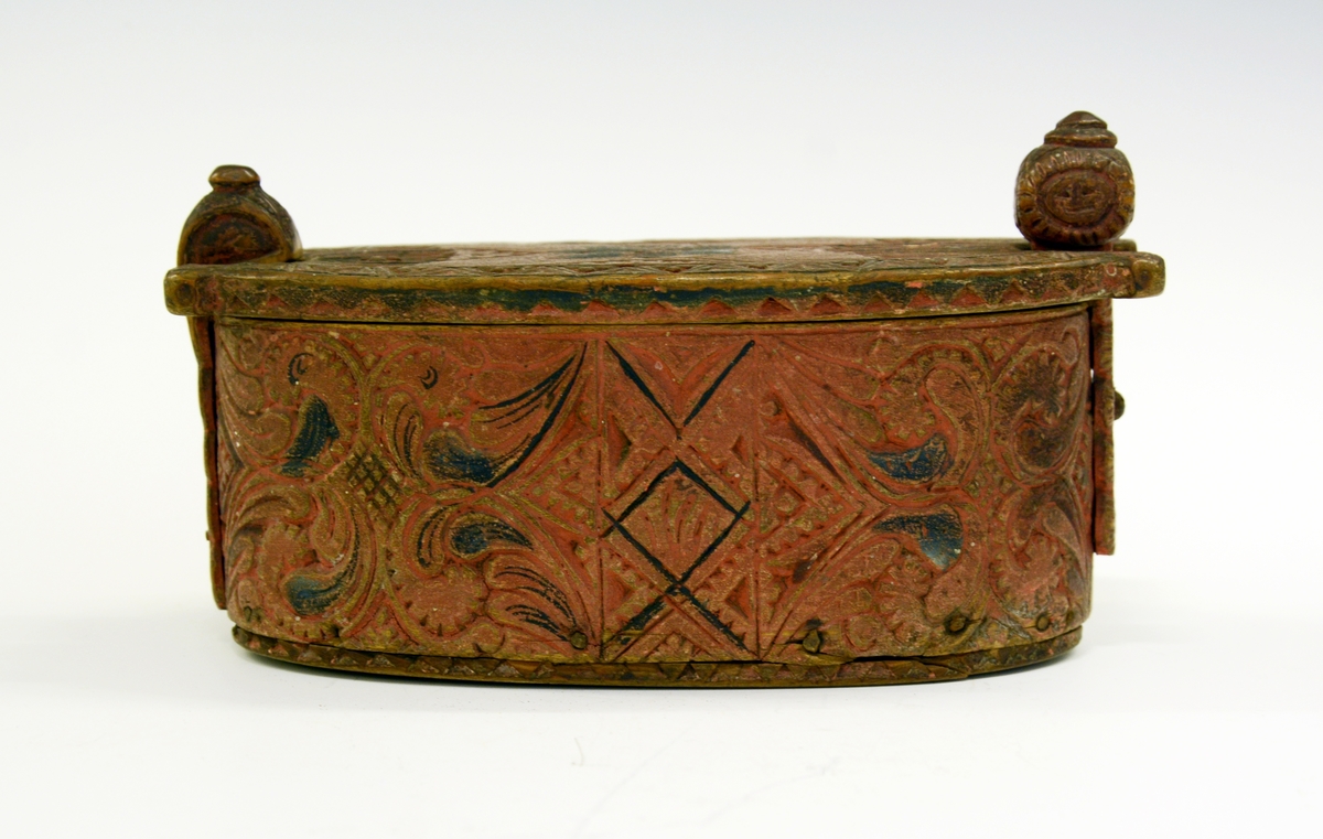 Tine av tre. Fra protokollen: Leikety-tine utskori i grovt kerbsnitt og plymrankkrullar. Under botnen skori 1814 og bokstavar. Standarane løglegt maksla som hovud med haarflettur. Raudmaala.