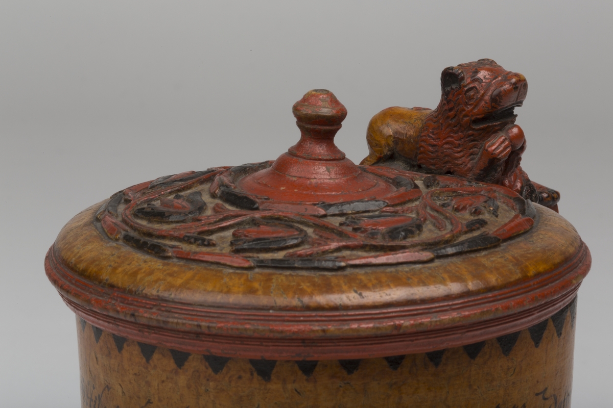 Dekorert med fortløpende billedfrise med dyr og trær på nederste del av korpus. Kannen har løveføtter og løvegjekk og bakkantine som håndtak. 