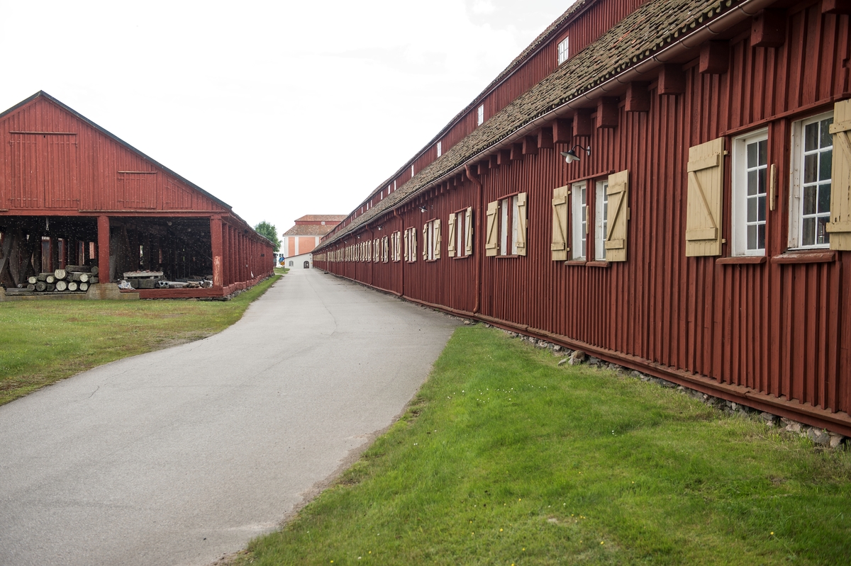 Fotodokumentation av byggnader på Lindholmen i Karlskrona.       Repslagarbanan t.h. är en av Karlskronas äldsta bevarade byggnader. Träbyggnaden är över 300 meter lång (1000 fot). Byggnaden tillkom på 1690-talet. Här tillverkades fram till år 1960 alla typer av tågvirke för seglande örlogsfartyg. I banhuvudena förbereddes hampan, råvaran till repen. När repslagarna slog repen gick de omväxlande framlänges och baklänges genom banan. År 1969 blev Repslagarbanan byggnadsminnesmärkt. Slitaget t v. byggdes omkring 1850 användes som virkesskjul. De runda träpelare ska ha varit utrangerade mastträn. Byggnaden är ca: 96 meter.