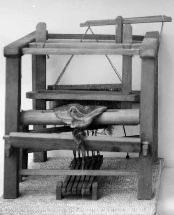 Liten modell av en flatvev med renning, vevskje, garnbom, slagbom, brystbom og trøer.