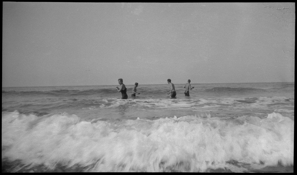 4 unge menn er ute og bader på en sandstrand med sanddyner.