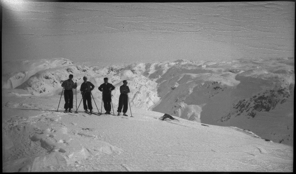 Fire unge menn på skitur fra Roalkvam til Stranddalen i Suldal. Det er bilder av hytter i fjellet, fra landskapet, lek med en hoppbakke og fra skigåing.