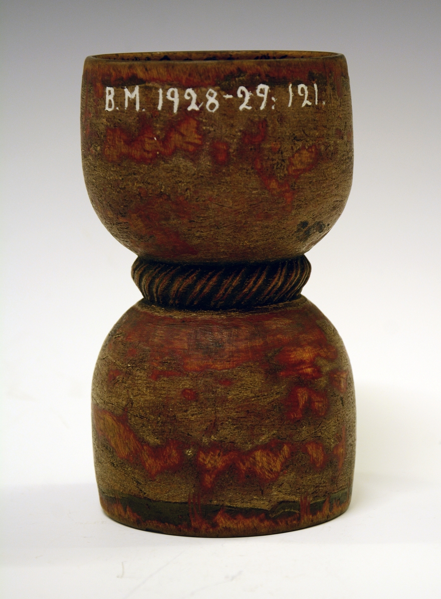 Dobbeltbeger. Fra protokollen: Bugge svarva av bjørk, maala. Baae staupi av paa lag same storleik, innsnørde med eit toglaga band. Utanpaa er den graa-raude maalingi noko avsliti, inni er rosemaala paa gul grunn med raude og grøne rosur, svart konturer. I det eine staupet er ein liten raud botnblom, og fraa denne gjeng mjuke rislur med tytebærblad paa. Kring tromi inni denne innskrift: "Bugen bruges i Fleng af Pige og Dreng". I det hitt staupet er maala eit stort firblad danna av 4 tulipanlaga blomar ut fraa ein botnblom. Millom tulipanane tytebærblad. Innskrift kring tromi inni "O.A.S.M. ANNO 1766"