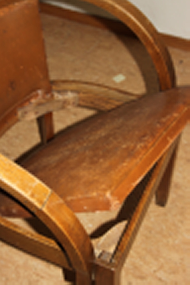 Møteromstol/kontorstol med armlener samt buet rygg. 4 ben. Metallbeslag under armlener. Brunt skinn i rygg og sete. Stolen er lakket med klar lakk. Originalt møbel innkjøpt til det nye Statsarkivet i Kristiansand i 1935.