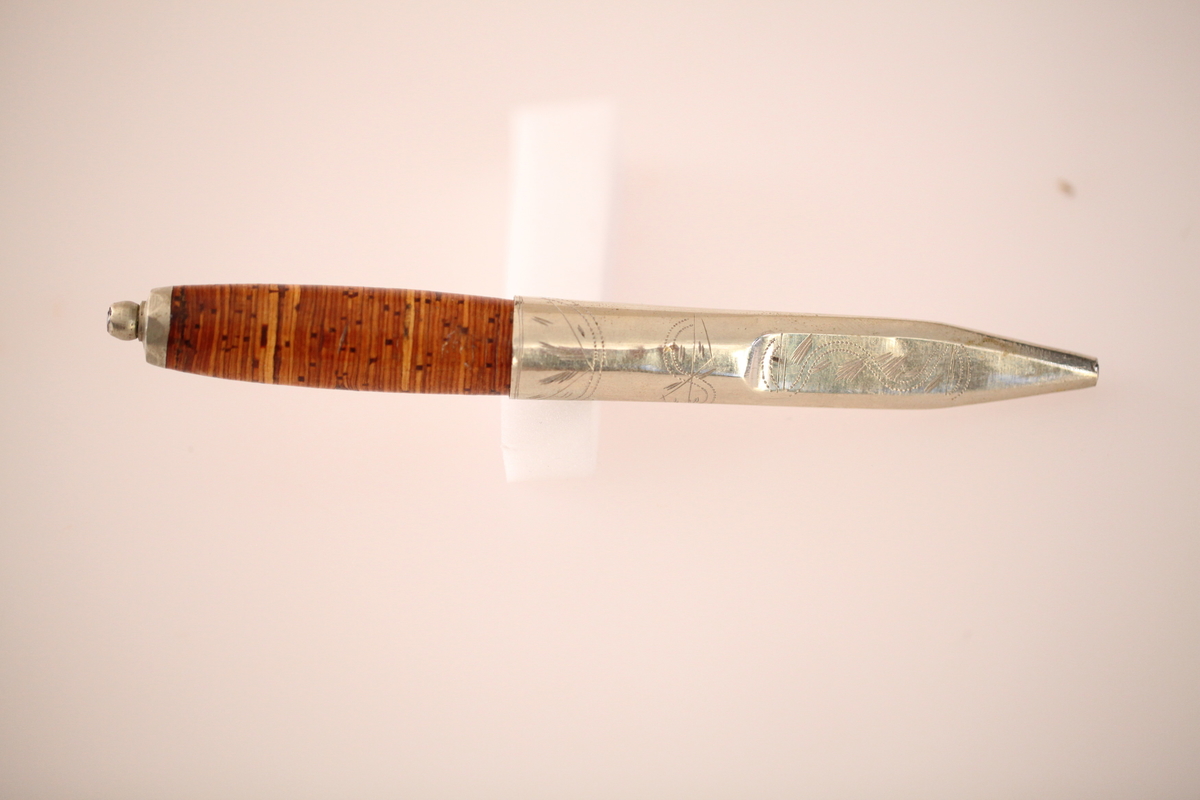 Kniv og slire hører ikke sammen. skaftet er laget av never, og slira er laget av nysølv. vanligvis hadde neverskaftkniver lærslire, og nysølvslirer hadde vanligvis ibenholdtskaft. Dekoren på slira er gravering og motivet er såkalte "Elstadkvister" slira er dermed høyest sannsynelig laget i Kolbu av en av Elstadkarene. Kniven har et fabrikkblad og er av ukjent opprinnelse.