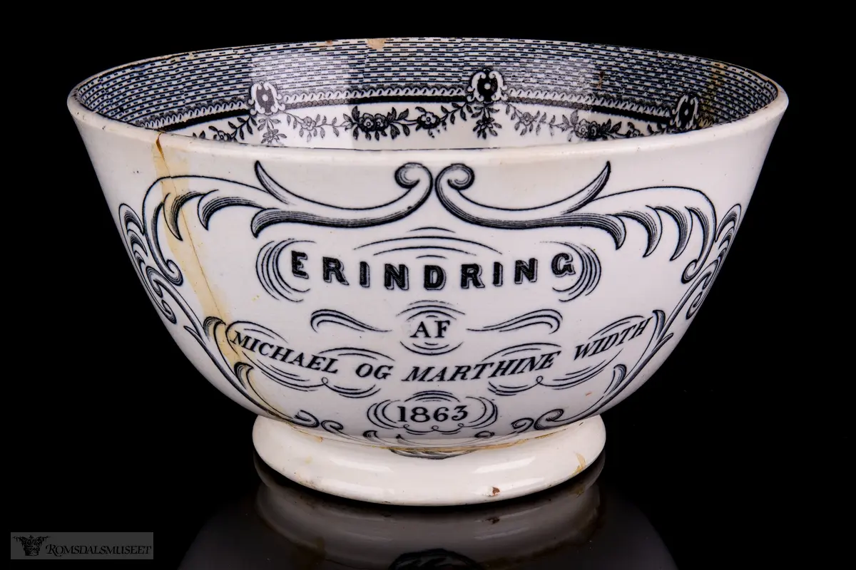 Innvendig et landskap med en klosterruin, hus og vegetasjon med vann rundt, og to kyr i forkant. På bollens sider er det et motiv med bebyggelse på en øy i en innsjø med seilbåter på vannet, fjell i bakgrunnen, og en borg eller landsby og to kyr i forgrunnen. Akantusranker rundt påskriften.