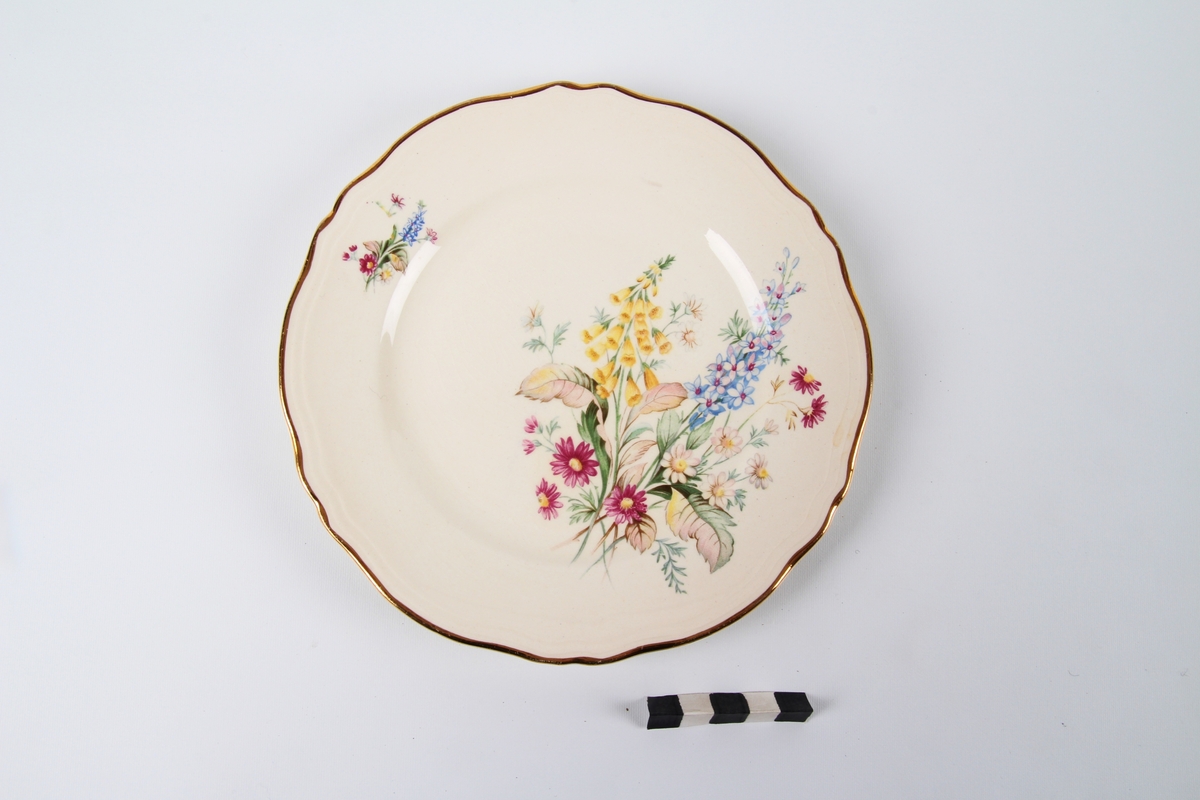 Tallerken med blomsterdekor og gullkant ytterst.