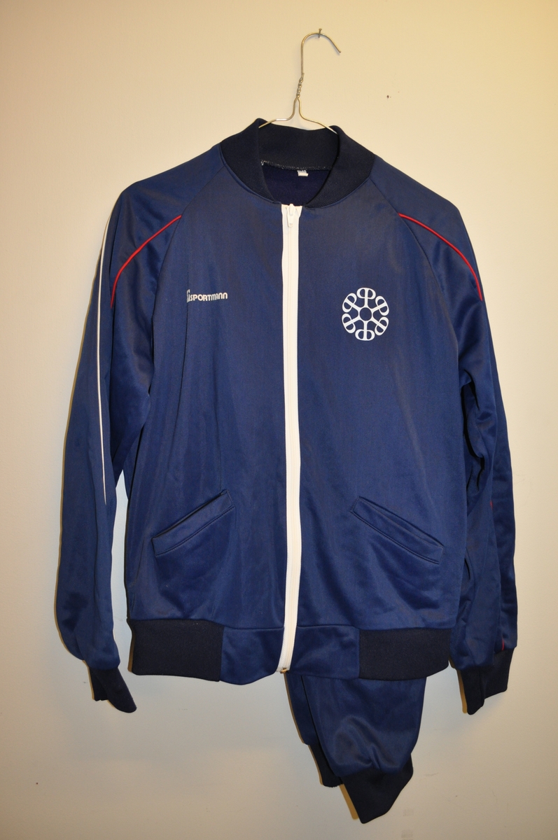 Treningsdress (bukse og jakke) med Postbankens logo og ordet "Sportsmann", samt ordet "Postsparebanken" på ryggen. Jakken har to stikklommer.  Størrelse 48.