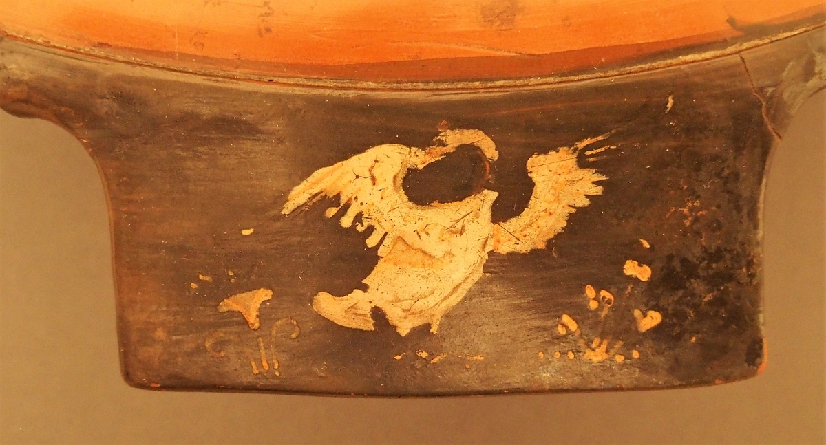 I skålens bunn naken mann (Dionysos) og kvinne med tamburin (mænade). Under dem en eggstav (kymation). Motivet er omgitt av løpende hund i sirkelform. På hankene hare og fugl. På undersiden palmettfrise (anthemion),løpende hund, mænade med tamburin og tromme og naken mann med olivengren (Apollon).