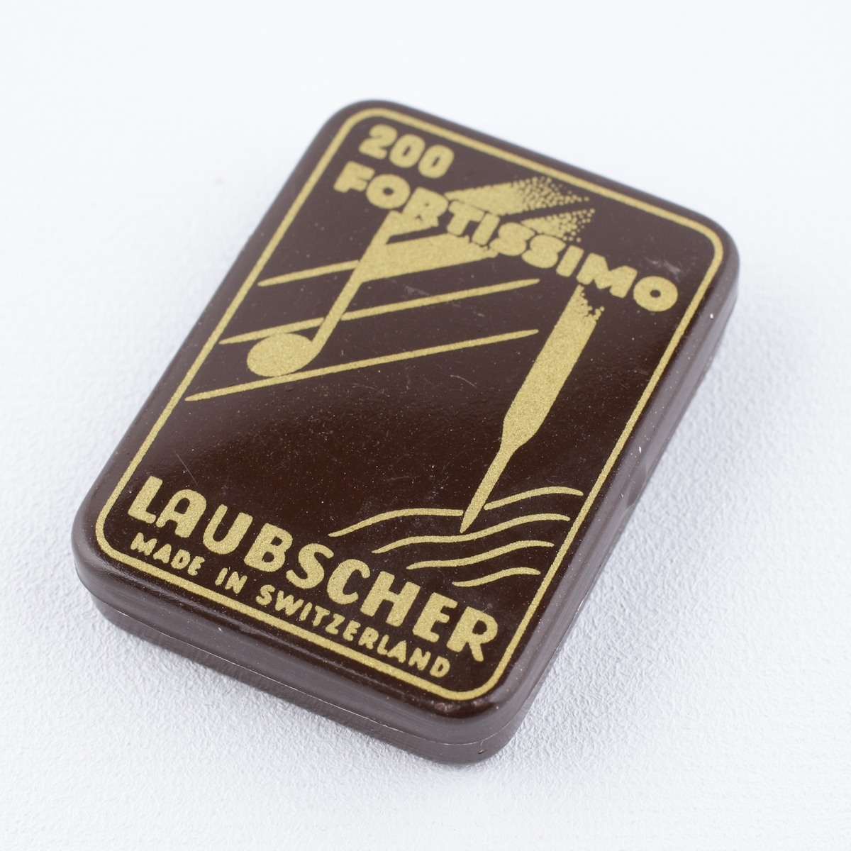 Ask av plåt.
Rektangulär modell med avrundade hörn. Lock med dekor i brunt och gulvitt. Text på locket: "200 Fortissimo, Laubscher, 
Made in Switzerland". 
Förvaringsask för grammofonnålar.