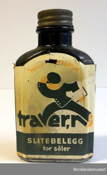 Glassflaske med sålebelegg. Skrukork i metall. Etikett med illustrasjon av gående figur. Mørkt innhold.