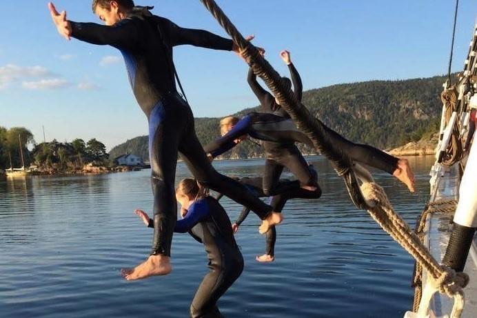 Fire ungdommer i svømmedrakt hopper i vannet fra skonnerten "Svanen". (Foto/Photo)