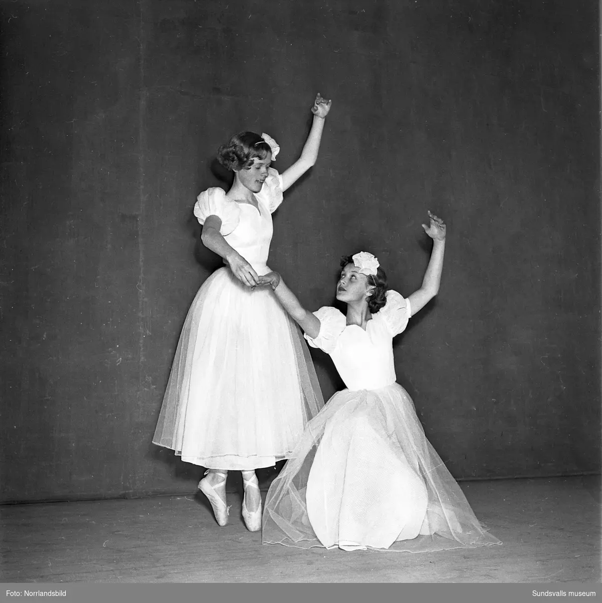 Två ballerinor poserar på en scen.