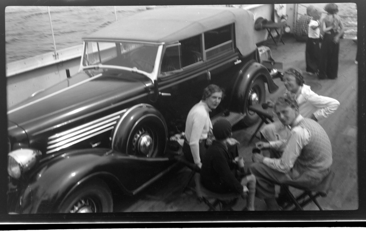 Hilda Sundt, Lars Peter Sundt, Julius Sundt og en ukjent person sitter ved siden av Rolf Sundt sr.'s nye Buick ombord på fergen mellom Langesund og Helgeroa. Fotografert 17. juli 1938. Buick årsmodell 1934-35, convertible sedan karossseri.