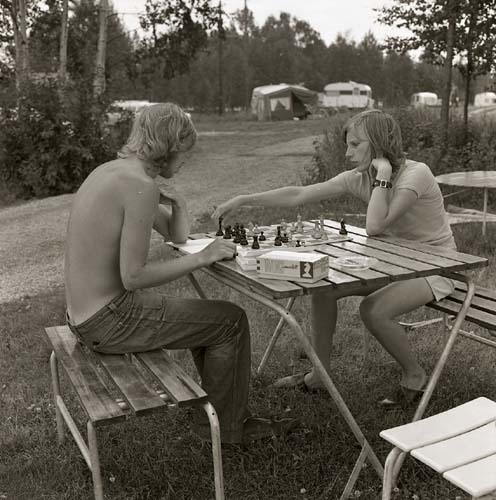 På en campingplats i Bollnäs sommaren 1967 - 1968. Två tonårspojkar sitter vid ett campingbord och spelar schack.