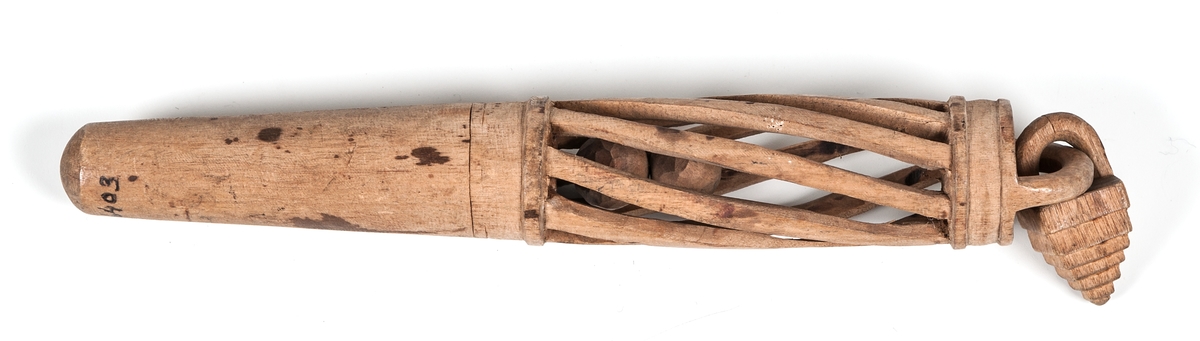 Nystpinne av trä av trä med vridet snidat genombrutet mönster. Innehåller två träkulor och vidhängande hänge i ena änden.