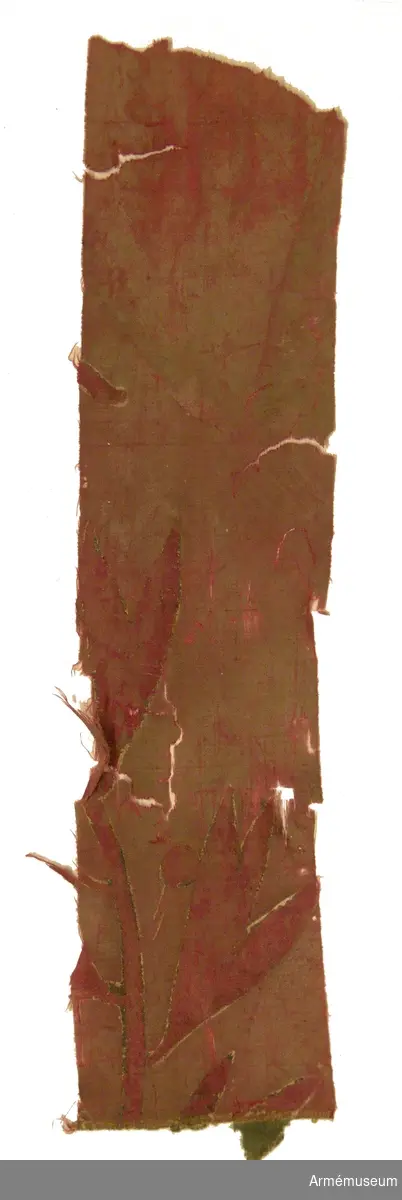 Fragment av duk av sidentaft med rutor i rött och grönt.

Två långsmala remsor, 1400 x 80 mm.

Två andra fragment finns av fanan, båda med separata accessionsnummer:
AM.068250 samt AM.068251.