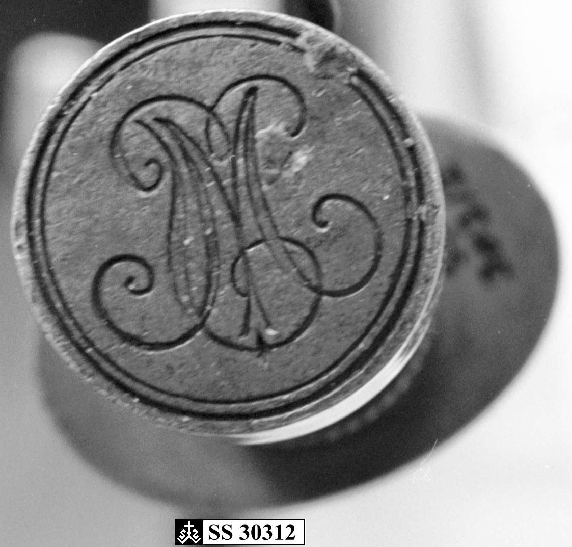 Stempel av messing med initialer på toppen av håndtaket.