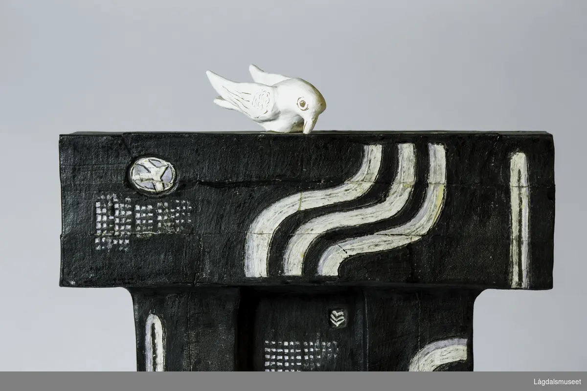 Portaal med en hvit fugl sittende på toppen. Under går eller står 14 enøyde figurer. Fem svarte og ni hvite.
