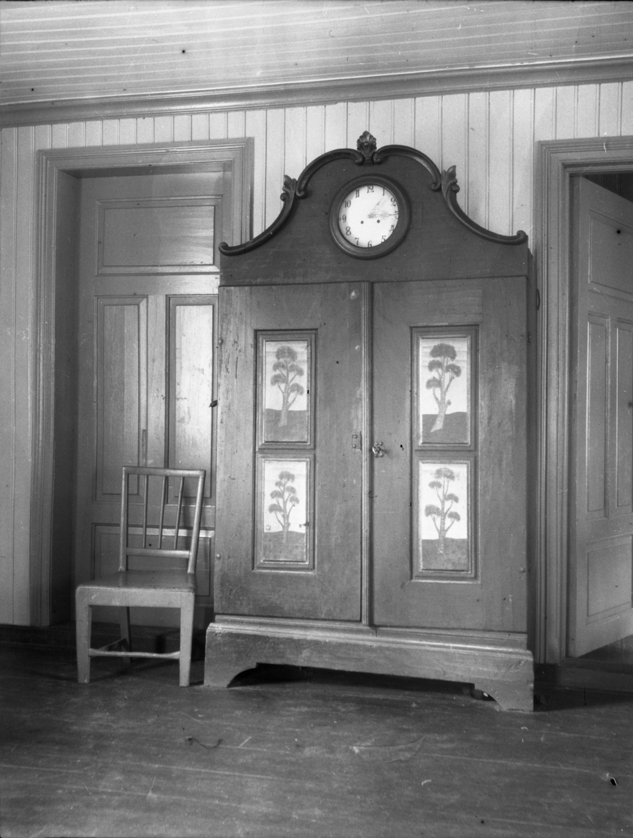 Rikard Berges fotoarkiv. Interiør. Dekorert skap med ur, Tynnset. Bildet er tatt av Johanna Bugge Berge. Fotografert 1906.