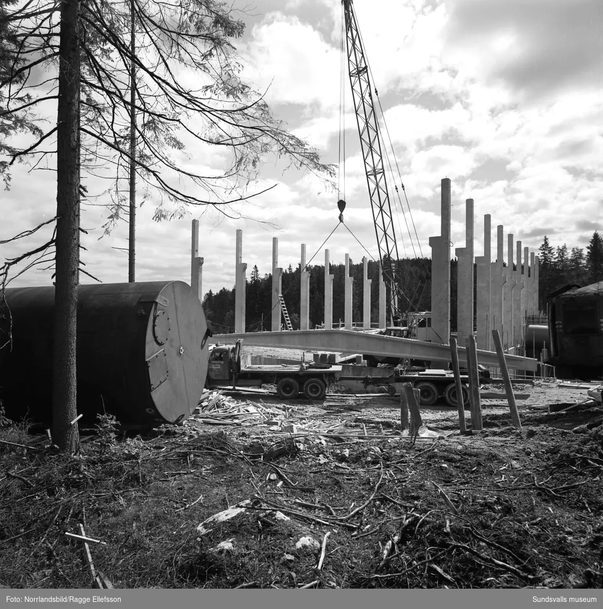 Takstolarna lyfts på plats vid bygget av Nyhamns kraftverk. En del av arbetarna är mer än lovligt våghalsiga och till synes helt bekväma med att arbeta på hög höjd.