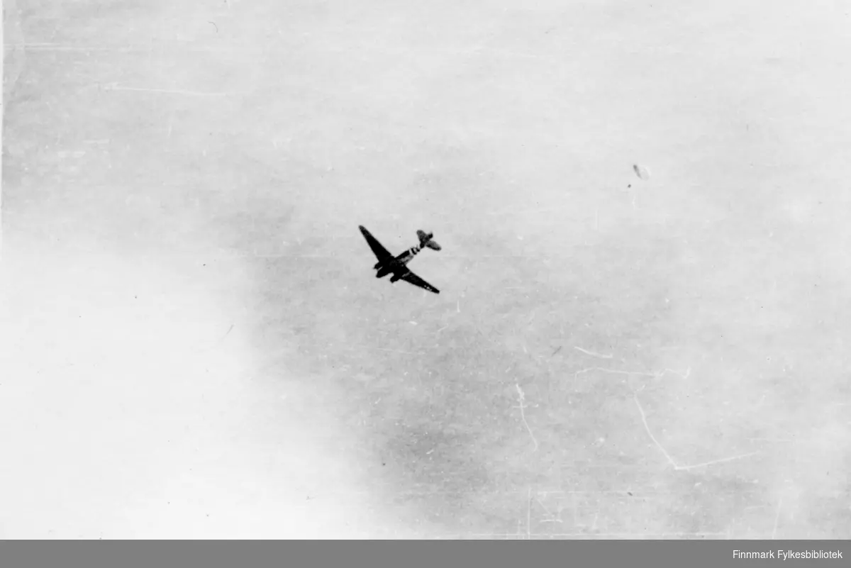Vingegeometrien og fargene foran halen tyder på at dette kan være en amerikansk C-47 transportfly, altså C47 Dakota fly. Sovjetunionen fikk flere hundre av disse på lend-lease fra USA under 2. verdenskrig. Fotografert av en soldat i 2.Bergkompani under frigjøringen av Finnmark.

Bildeserien "Frigjøringen av Finnmark 1944-45" viser et unikt materiale fotografert av soldater i Den Norske Brigade, 2. Bergkompani under deres oppdrag "Frigjøringen av Finnmark" som kom i stand under dekknavn "Øvelse Crofter". Fakta rundt dette bildematerialet illustrerer iflg. vår informant, George Bratli: "2.Bergkompani, tilhørende Den Norske Brigade i Skottland,  reiste fra Skottland 30. oktober 1944 med krysseren «Berwick» til Scapa Flow på Orkenøyene for å slutte seg til en større konvoi som skulle være med til Norge. Om bord på andre skip var det mange russiske krigsfanger som hadde vært på tysk side og som nå ble sendt hjem. 
2.Bergkompani forlot havn 1.november 1944 og kom til Murmansk, Sovjetunionen, 6. november 1944. 
De ble her lastet om og fraktet til Petsamo, Sovjetunionen, hvor de ankommer 11.november 1944. 
Kompaniet reiser så til Sandnes utenfor Kirkenes og blir forlagt der frem til 26.november 1944. De flytter så videre til Skipparggura. 
Den 29.november reiser deler an kompaniet til Rustefielbma og Smalfjord og noen drar opp på Ifjordfjellet. 

17. desember ankommer resten av kompaniet til Smalfjord. 30.desember blir en avdeling sendt til Hopseide og 8. januar 1945 blir noen sendt til Kunes.
Den 14. januar er kompaniet delt og ligger i Kunes, Kjæs, Børselv, Hopseide og Smalfjord.
5. februar 1945 blir 3.tropp sendt over Porsangerfjorden for å operere i Olderfjorden. Her var de i kamp og hadde tap i  Billefjord og Sortvik.
8.mars 1945 kom noen til Renøy og 12. mars kom første del av kompaniet til Brennelv.
7.mai begynte kompaniet å bygge ny kai i Hambukt.
19. mai ble de som hadde falt begravd i Lakselv.
8. juni ble kompaniet flyttet fra Brennelv til Tromsø for så å bli sendt videre til Mo I Rana 16.juni."

Nasjonalbiblioteket har et hefte fra 1983 skrevet av Krigsinvalideforbundet, med intervjuer med soldater og deres opplevelser: 
https://www.nb.no/items/5d58d366b390666f671f57078519c2c7?page=0&searchText=Det%20glemte%20kompani%20-%202.%20Bergkompani%20og%20frigj%C3%B8ringen%20av%20Finnmark

https://www.arkivverket.no/utforsk-arkivene/andre-verdenskrig/befolkede-jordhuler-kjokken-i-det-fri-og-midlertidige-begravelser-privat-bildesamling-etter-soldat-i-2.bergkompani
