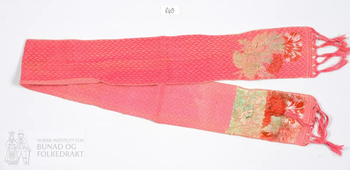 Rektangulært skjerf. Litt tynt halsskjerf i en myk og fin ullkvalitet/bomull/silke? Mønstret bunn i rosafarger. Brosjerte, flerfargede blomster i begge ender, med flotterende silketråder på baksiden. Lange, knytte frynser av trådene i stoffet.
