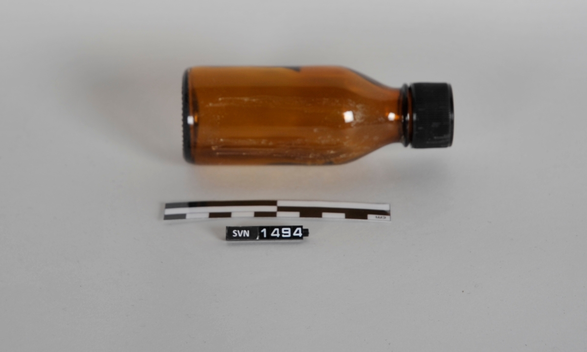 Brun sylindrisk flaske med sort kork