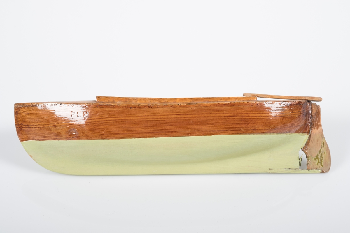 Liten lekebåt i tre/ modell av sørlandssnekke med ror og en liten propoell. Båten er lakkert grønn under vannlinjen og navnet "Per" er brent inn på begge sider.