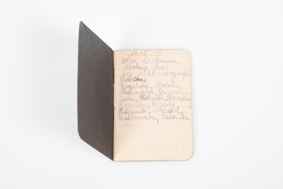 Svart minnebok i perm av tykt papir med mønster som ligner skinn. Linjert papir med "autografer fra krigsfanger".