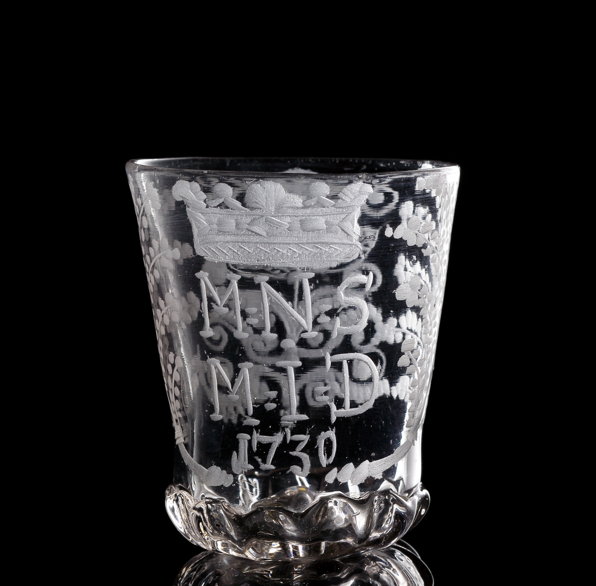 Bägare.
Beskrivning: Pålagt glas kring bottenpartiet. Liten syffel i botten. 
Graverad krona och växtmotiv samt text: M.N.S.M.I.D. 1730.
Färg: Svagt gråviolett klarglas.

Inskrivet i huvudkatalogen 1937.